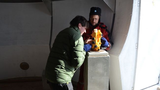 Stephen Bracke gets a hand from engineer Johnny Gaelens as he takes measurements of Earth's magnetic field in the shelter the station team set up this season for the GEOMAG project. - © International Polar Foundation / Alain Hubert