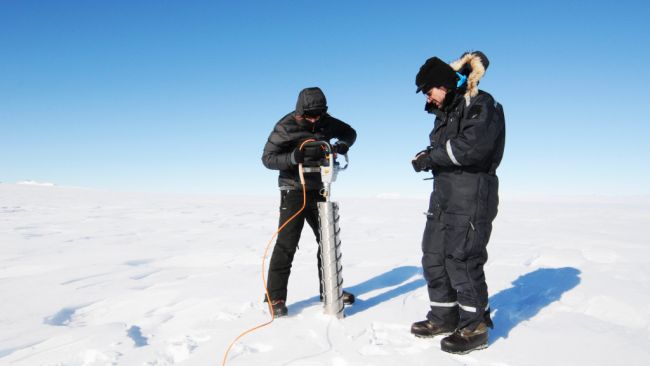 Preben Van Overmeiren and Alexis Merlaud are getting ready to use their special drill to collect samples of packed snow at different depths. - © International Polar Foundation