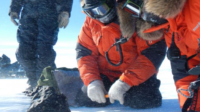 Belgo-Japanese SAMBA meteorite team members examining an 18kg meteorite found during a field trip on the Nansen Ice Field, 140km south of Princess Elisabeth Antarctica, during the BELARE 2012-2013 expedition.  - © International Polar Foundation/Vinciane Debaille