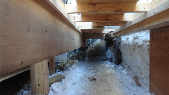 The flexible foundations are composed of long wooden beams that support the structure of the garages. One end of each beam is attached to the granite ridge underneath the station, while the other end can slide on adjustable platforms anchored into the ice. Here is the granite side under the entrance hall. - © International Polar Foundation / Alain Hubert