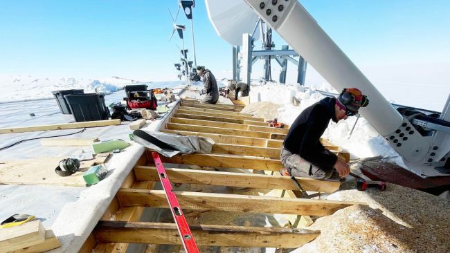 Carpenters lay the beams for the new protective covering between the annex roof and the ridge. - © International Polar Foundation