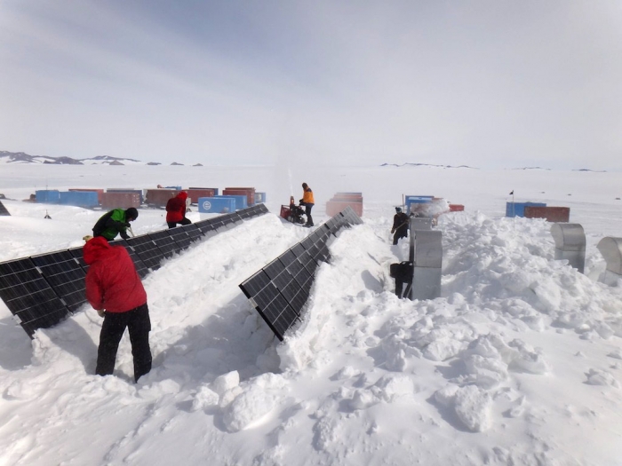 Removing the snow from the solar panels before taking them out. - International Polar Foundation