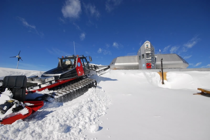 The garage hidden under the snow and the Prinoth tractor going at it... - International Polar Foundation / René Robert