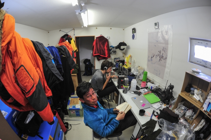 Belgo-Japanese SAMBA meteorite team working in the office mobile unit at the basecamp on the plateau,  on the Nansen Ice Field, 140km south of Princess Elisabeth Antarctica, during the BELARE 2012-2013 expedition.  - International Polar Foundation