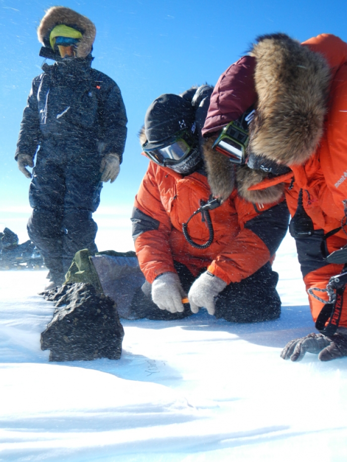 Belgo-Japanese SAMBA meteorite team members examining an 18kg meteorite found during a field trip on the Nansen Ice Field, 140km south of Princess Elisabeth Antarctica, during the BELARE 2012-2013 expedition.  - International Polar Foundation/Vinciane Debaille