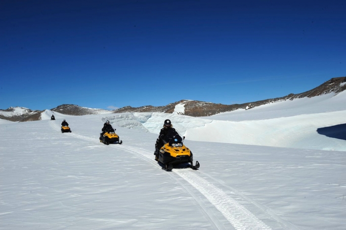 Land reconnaissance with the pilots: they will have to use ski-doos since they are still waiting for their helicopters. - International Polar Foundation