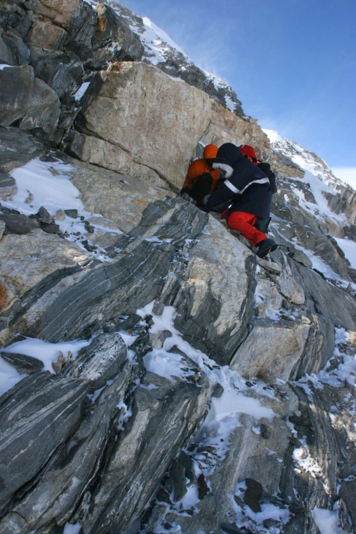 Up a small cliff: geologists have some climbing experience, and our field guide is there for assistance. - International Polar Foundation